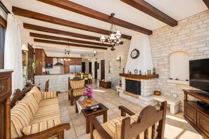 Un salon spacieux avec une cheminée, des meubles en bois et un mur en pierre.