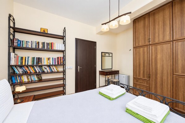A bedroom with a bed, a bookshelf, a wardrobe, and a bedside table.