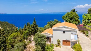 Una casa costera con vistas al mar, rodeada de vegetación.