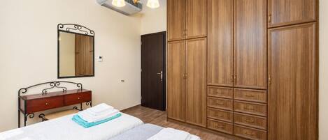 A bedroom with a bed, a dresser, a wardrobe, a mirror, and a ceiling fan.