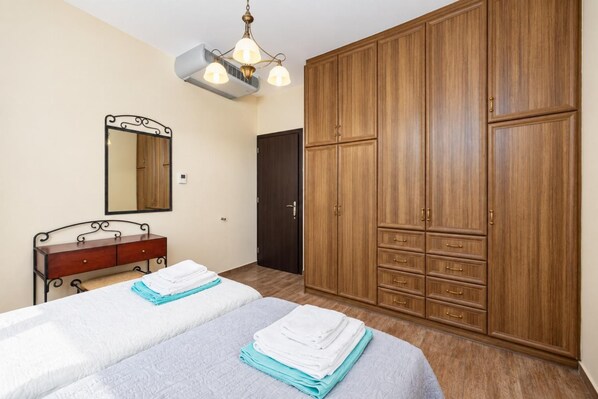 A bedroom with a bed, a dresser, a wardrobe, a mirror, and a ceiling fan.
