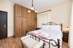 Une chambre à coucher comprenant un lit, une armoire, une chaise et une table de chevet.