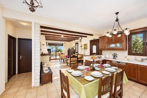 A spacious kitchen with wooden cabinets, a dining area with a table set for six, and a view through the glass door.