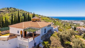 Una vila blanca amb teulada, un balcó i vista al mar.