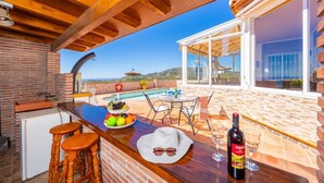 Zona de bar amb vista a la piscina, una paret de maó i un sostre de fusta.