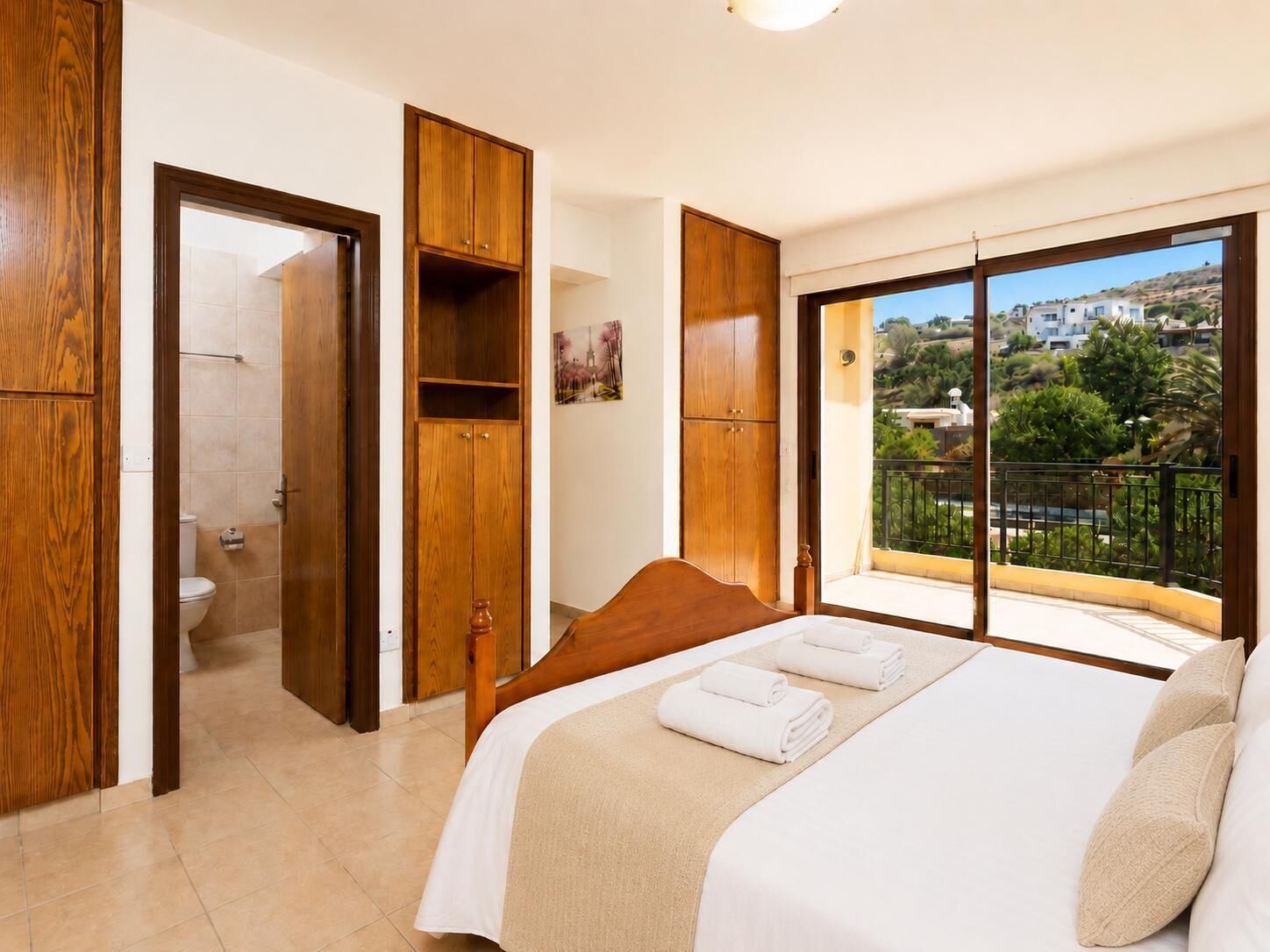 Un dormitorio con cama, armario de madera y baño completo con inodoro y ducha.