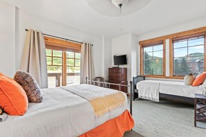 A bedroom with a bed, a dresser, a chair, a TV, and large windows. - KBM Resorts | Town Pointe | 1 level with views of mountains, Walk to Main and Town Lift, Elevator access, Parking, A/C! TPC-301c (Park City)