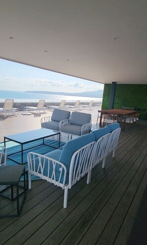 Relax in a seaside retreat with a covered outdoor seating area featuring lounge chairs and a table.