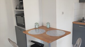 A compact kitchenette with a built-in oven, a coffee maker, and a small trash bin. - Le Vert Galant (Morsang-sur-Orge)
