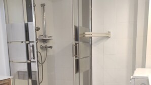 A glass-enclosed shower area with a handheld showerhead and a wall-mounted faucet. - Le Vert Galant (Morsang-sur-Orge)
