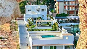 Un hôtel moderne doté d’une piscine, entouré de verdure et offrant une vue sur un paysage montagneux.