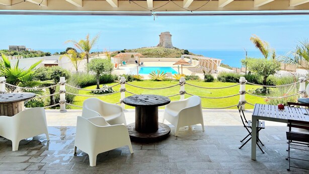 Une terrasse extérieure avec vue sur la mer, une piscine et une tour.