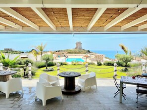 Un patio exterior con vista al mar, una piscina y una torre.
