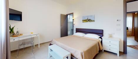 Una habitación de hotel moderna con cama, mesita de noche, escritorio, silla y un cuadro en la pared.