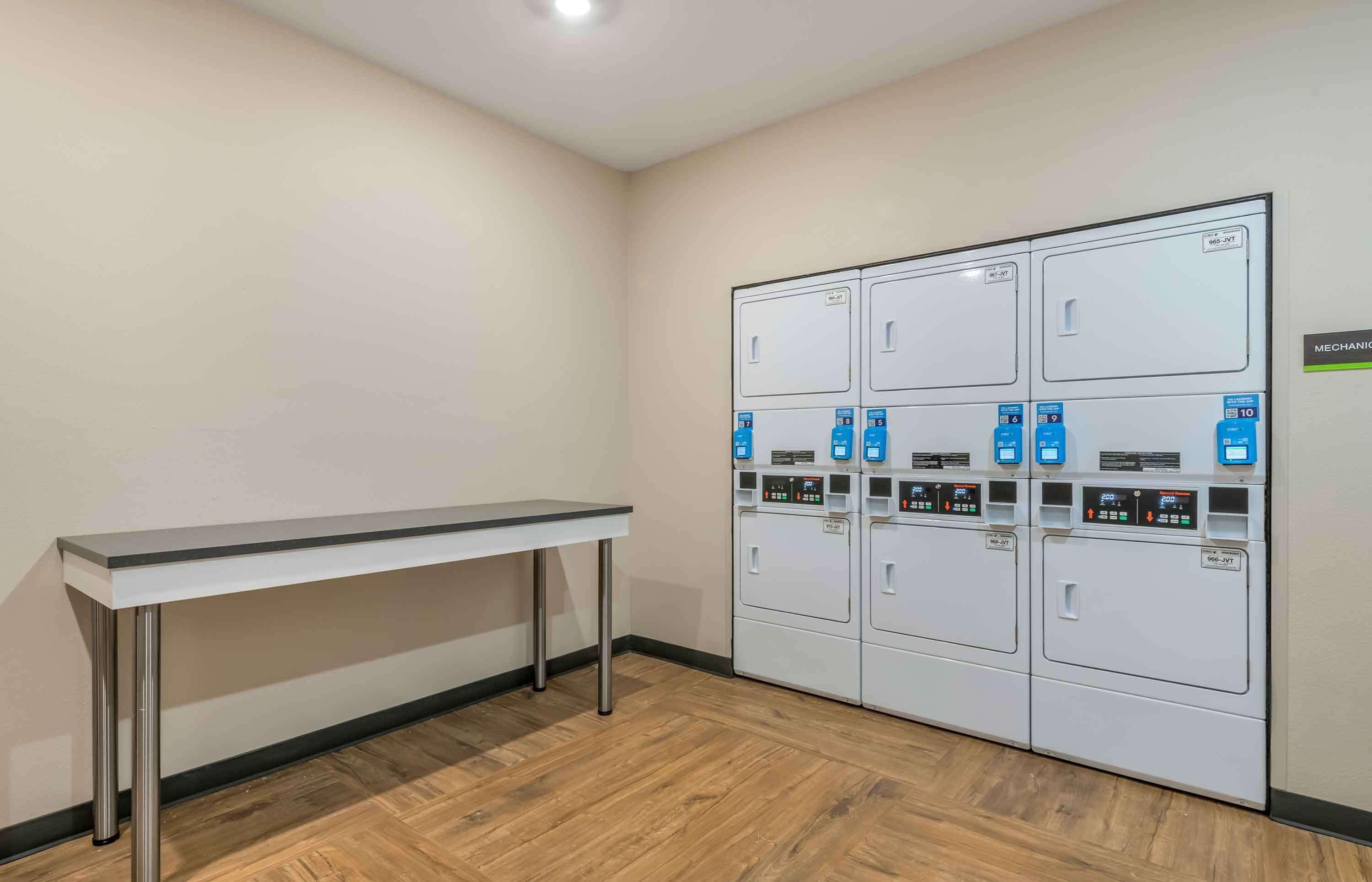 A laundry room with a long table and multiple washing machines.
