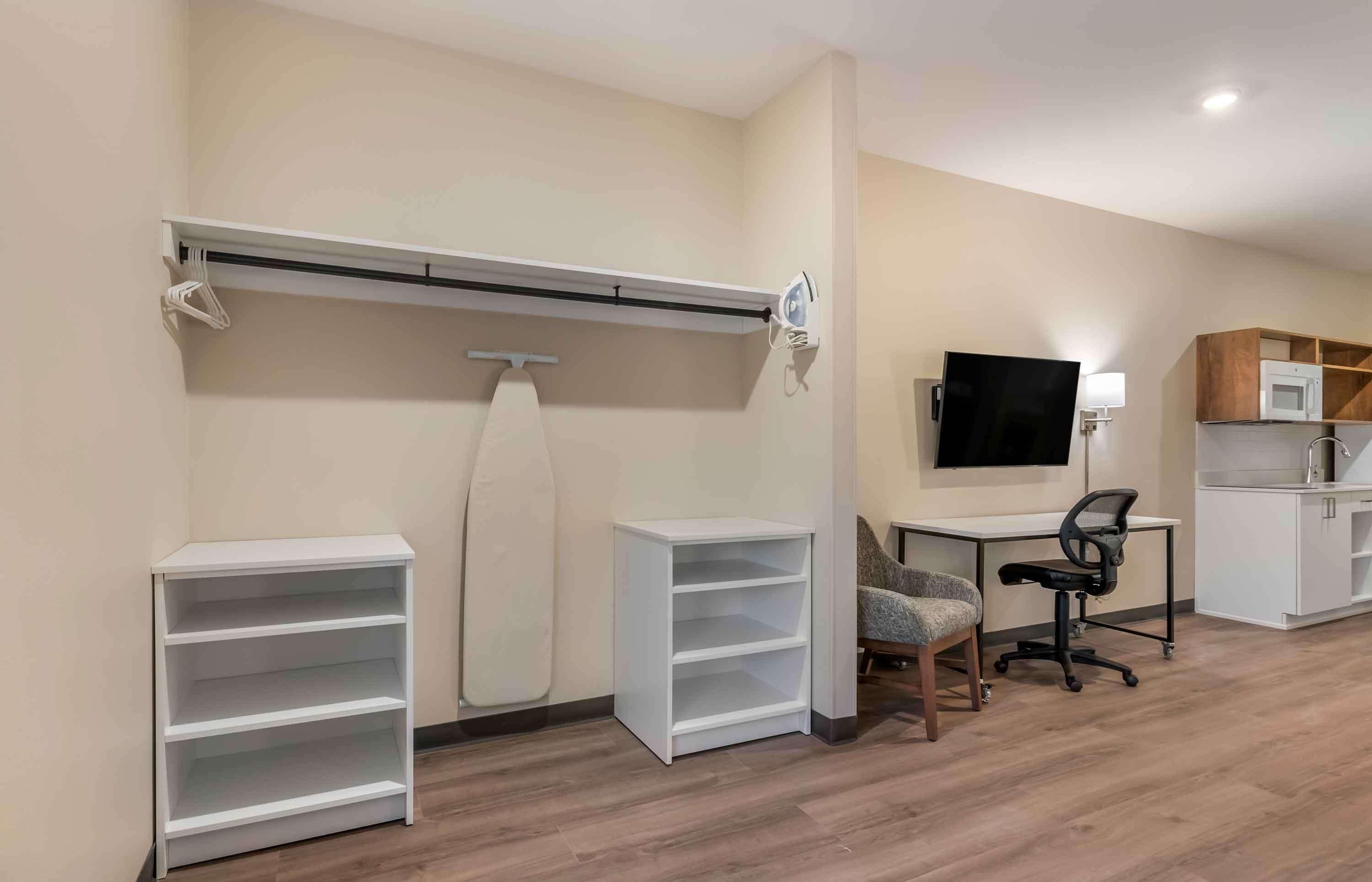 A modern room with a desk, chair, TV, and built-in shelves.
