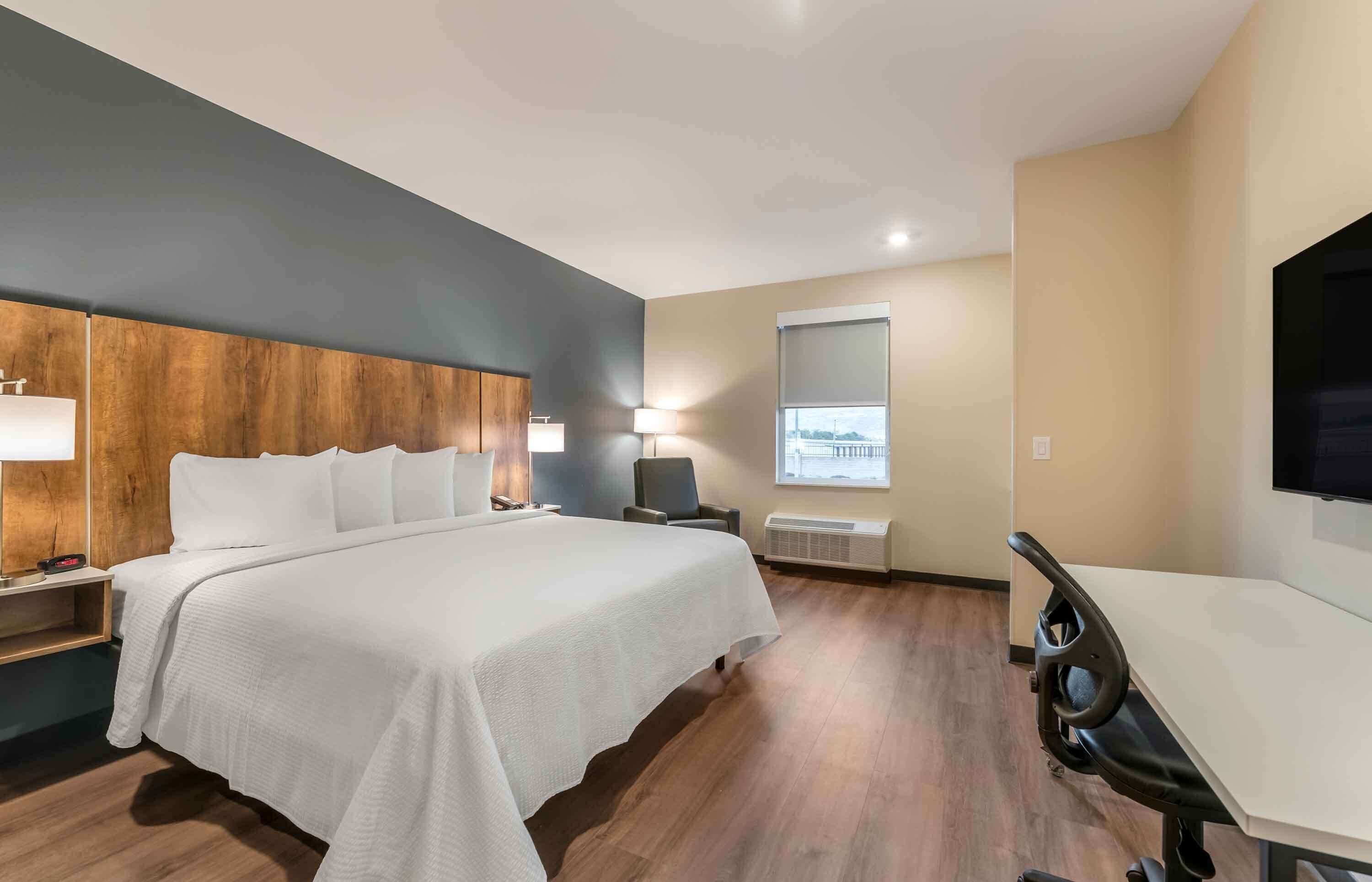 A modern hotel room with a large bed, bedside tables, a desk, and a chair.