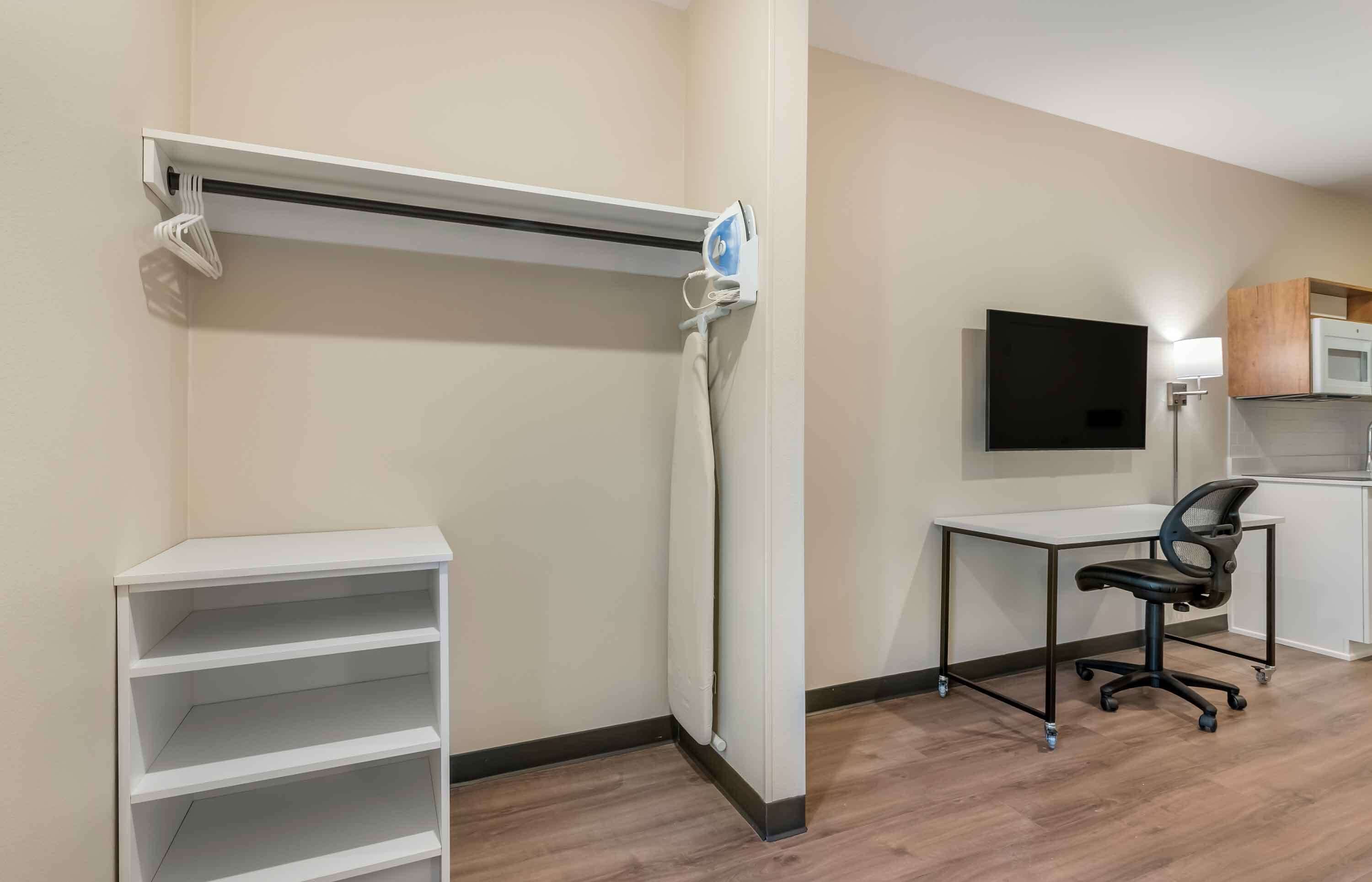A modern office space with a white desk, black office chair, and a mounted flat-screen TV.