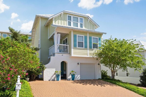 Une maison à deux étages avec un balcon, un garage et une allée pavée en briques.