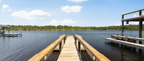A wooden pier extending into calm water, surrounded by a forested shoreline.