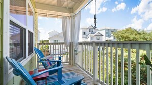 A covered porch with blue Adirondack chairs, a ceiling fan, and a view of neighboring houses. - 30A Beach House - Pelican's Rest by PHG (Panama City Beach)