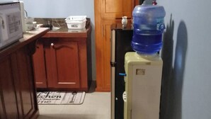 Uma cozinha compacta com armários de madeira, geladeira, micro-ondas e dispenser de água.