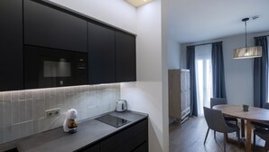 Una cocina moderna con armarios oscuros, horno integrado y una cafetera sobre la encimera.