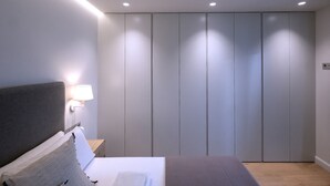 Une chambre à coucher moderne avec un lit, une table de chevet et une lampe fixée au mur.