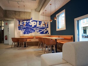 A modern interior with a blue accent wall, seating arrangements, and pendant lighting.