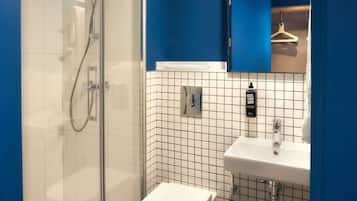 Un baño moderno con ducha acristalada, lavabo blanco y una pared de acento azul.