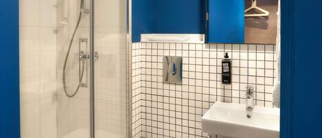 A modern bathroom with a glass-enclosed shower, a white sink, and a blue accent wall.