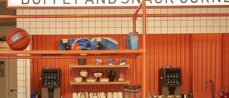 Zona de bufé y snacks, con letrero, estantes con alimentos y electrodomésticos de cocina.