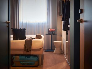 Una habitación de hotel con cama, maleta, televisor y un inodoro.