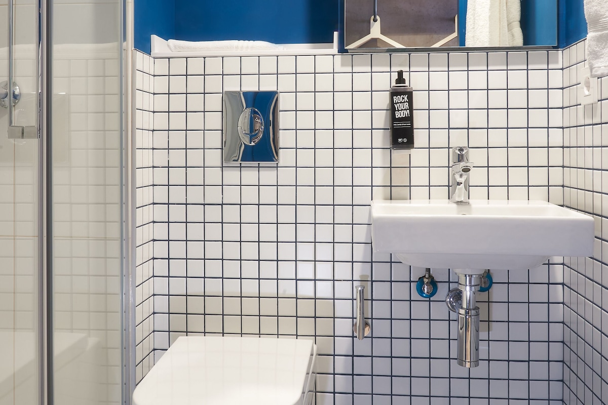 Une salle de bain avec des toilettes blanches, un lavabo et un espace douche.