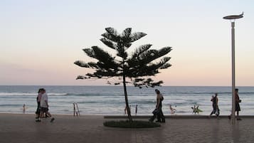Di pantai, pasir putih, kursi berjemur, dan payung pantai