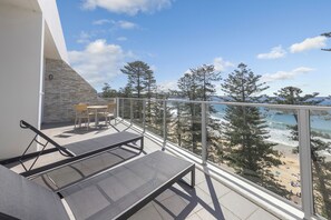 A balcony with a view of the beach, outdoor furniture, and a stone wall. - Peppers Manly Beach (Manly)
