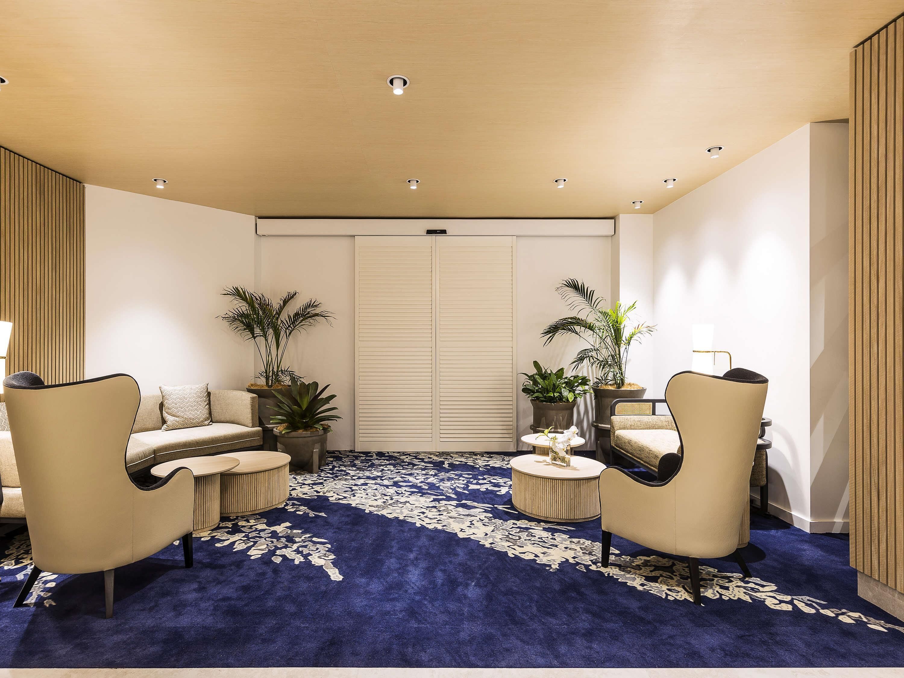 A modern room with a blue carpet, two sofas, a coffee table, and potted plants.