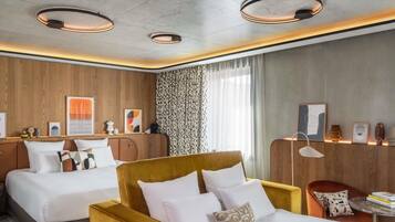 A hotel room with two beds, a sofa, a small table, and a chair.