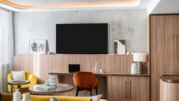 A modern living room with a flat-screen TV, wooden furniture, and a yellow sofa.