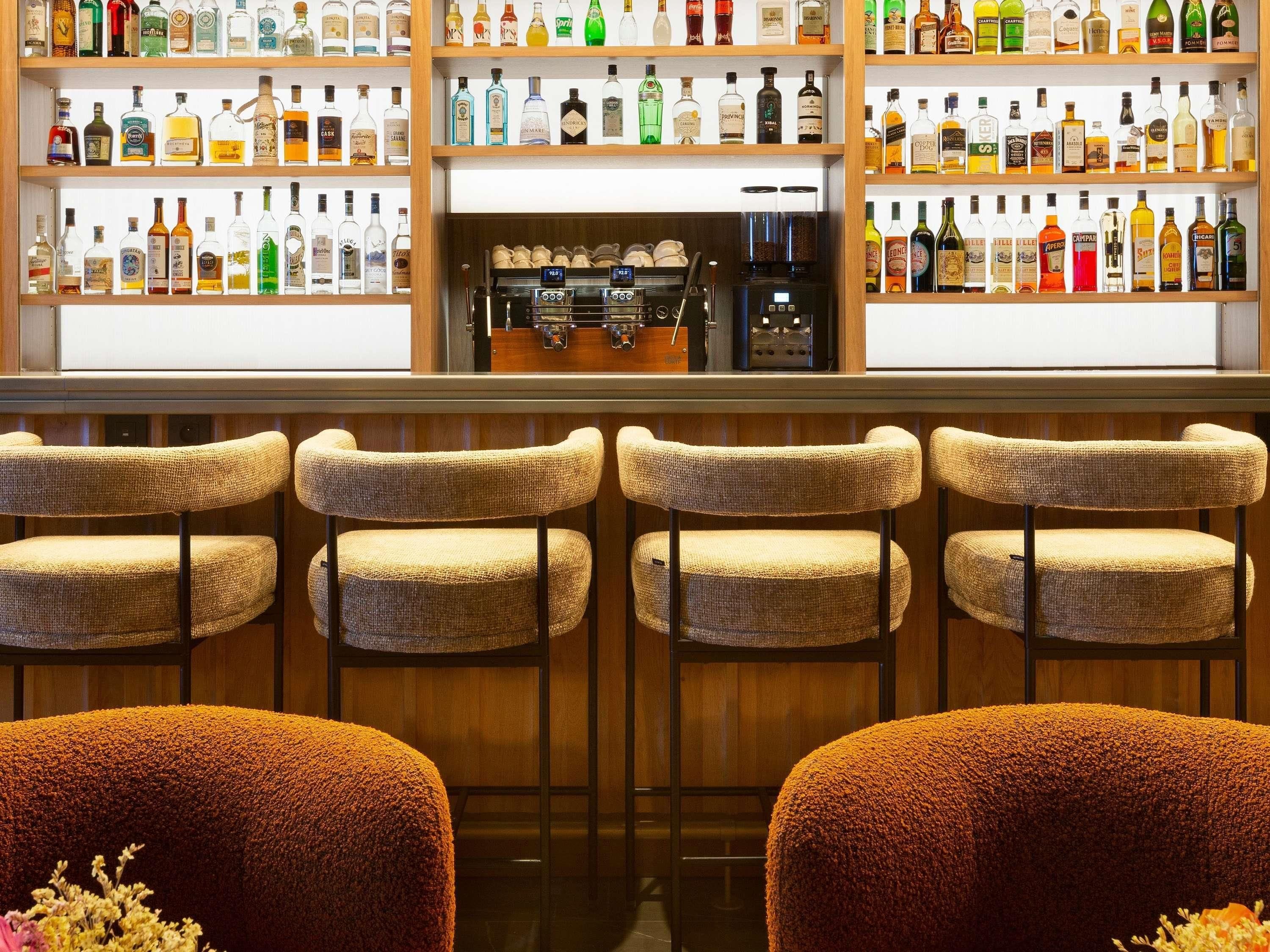 Zona de bar con varios taburetes y estanterías llenas de botellas de licor.