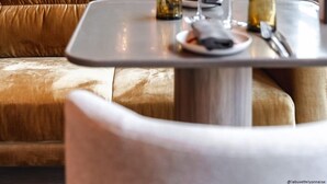 Un comedor moderno con una mesa de madera preparada para dos personas, rodeada de asientos cómodos.