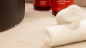 A hand dispensing lotion from a Clarins bottle into a bowl. - Pullman Lyon  (Lyon)