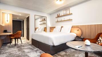 Ein Hotelzimmer mit einem Bett, einem Schreibtisch, einem Sessel, einem runden Tisch und einer Couch.