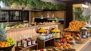 A buffet with various food items, a kitchen area, and some greenery.