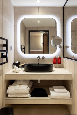 A modern bathroom with a large mirror, a round sink, and neatly folded towels. - Pullman Lyon  (Lyon)
