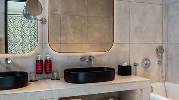 A modern bathroom with two sinks, a large mirror, a bathtub, and a towel rack.