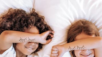 Two people lying in bed with white bedding.