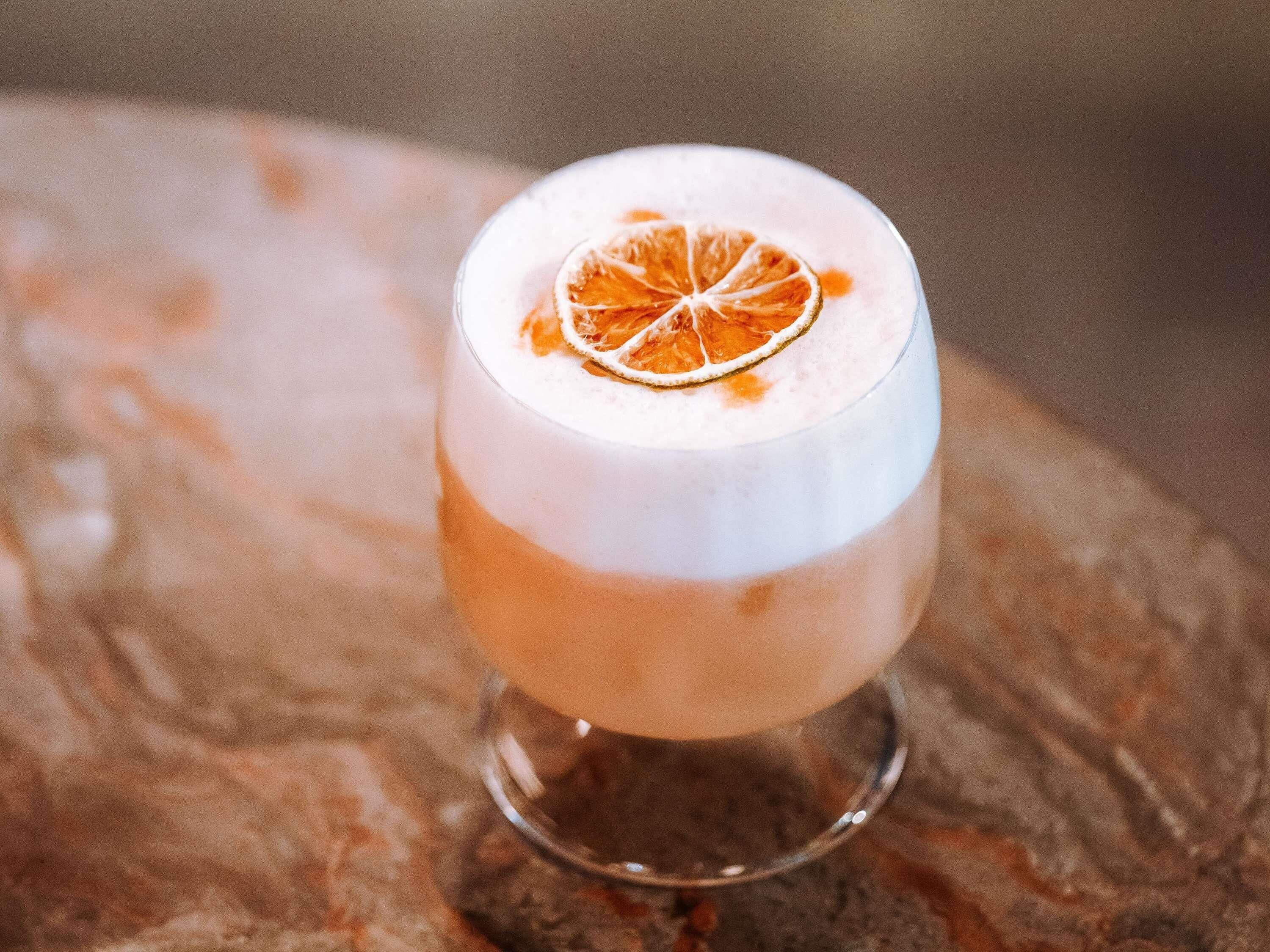 Un cóctel en un vaso con una rodaja de naranja.