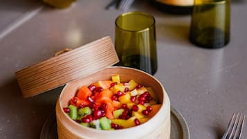 Un saladier en bois avec un couvercle, contenant une salade de fruits présentée dans une assiette.
