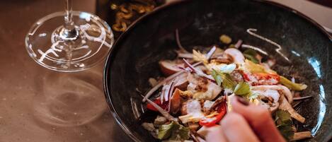 A dining table with a bowl of salad and a glass of white wine.